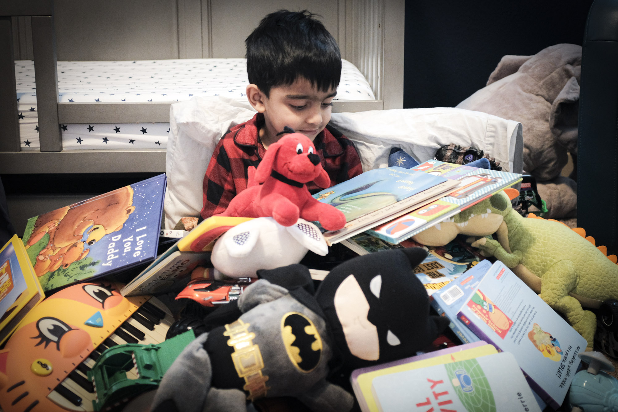 A child sitting between a pile of toys